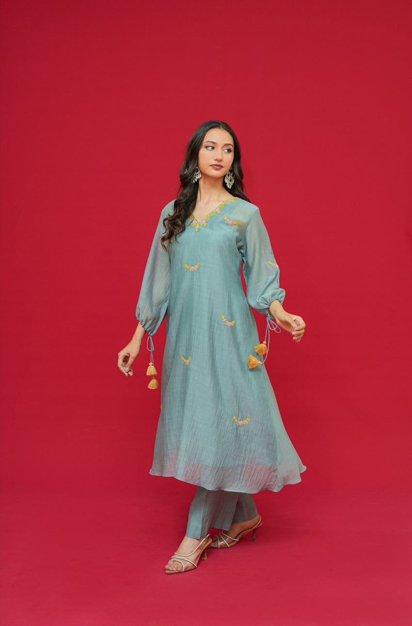 Woman wearing a light blue traditional outfit with gold details on a red background