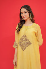 Woman wearing a yellow dress with intricate design on a red background