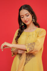 Woman wearing a yellow traditional outfit with intricate designs on a red background