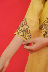 Yellow sleeve with intricate black embroidery on a red background