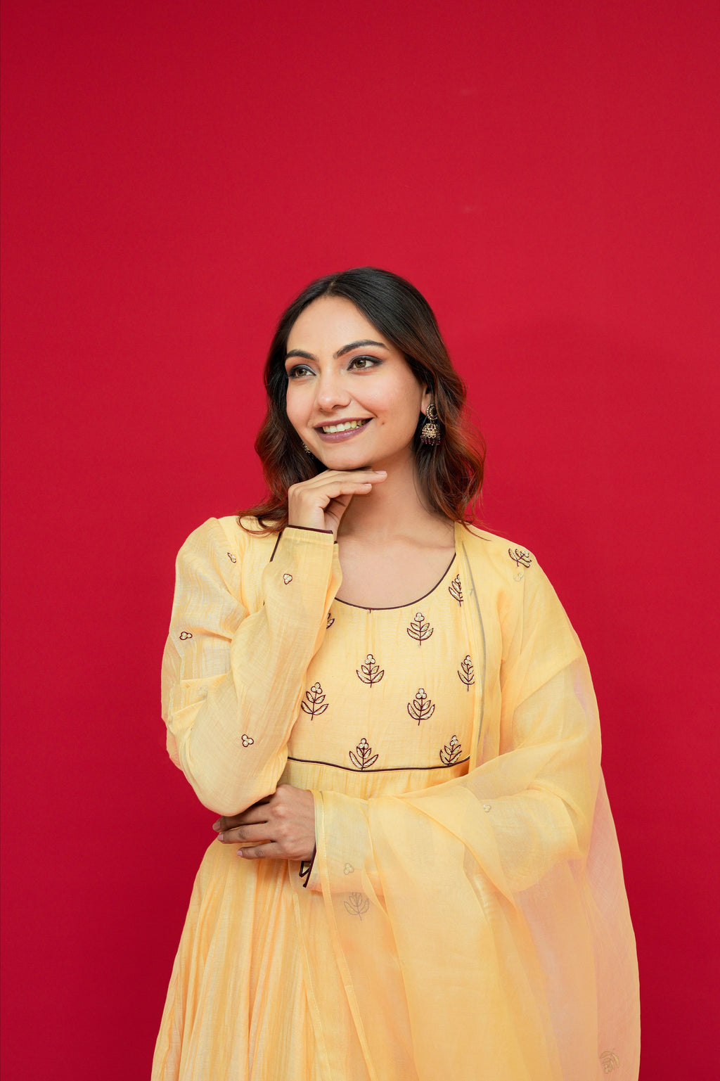 Woman wearing a Sunny Yellow Mul Chanderi Anarkali Set  against a red background