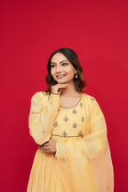 Woman wearing a Sunny Yellow Mul Chanderi Anarkali Set  against a red background