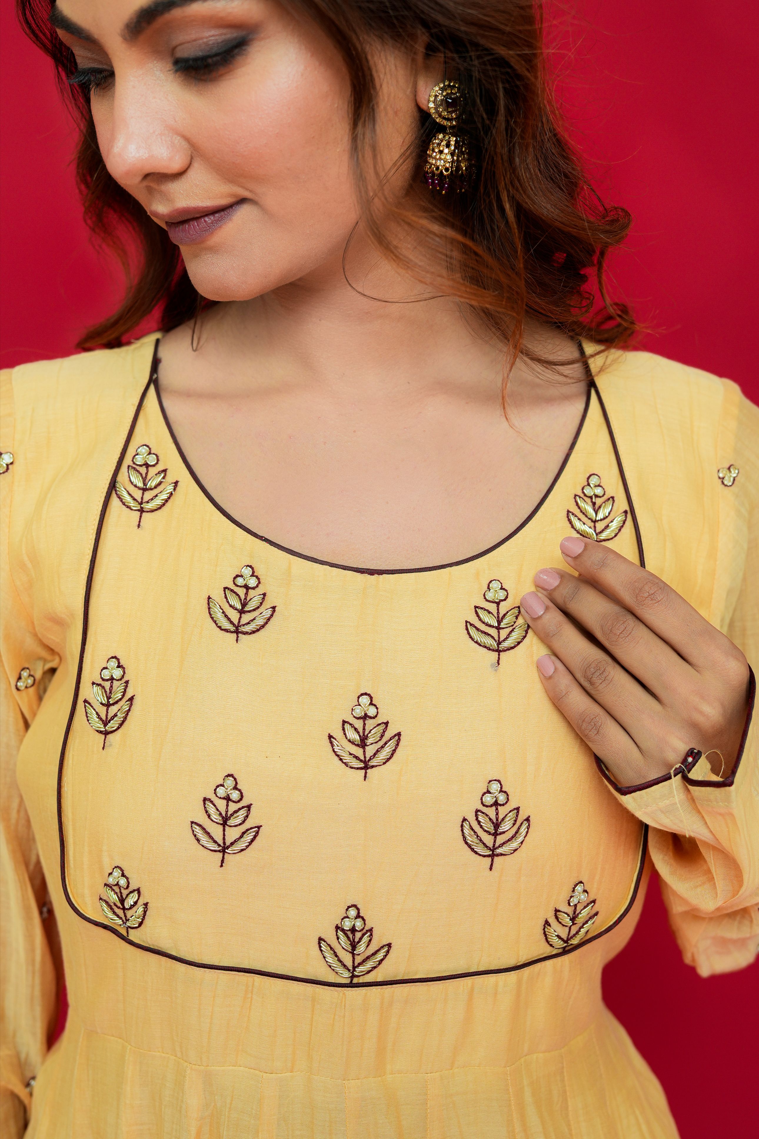 Woman wearing a Sunny Yellow Mul Chanderi Anarkali Set against a red background