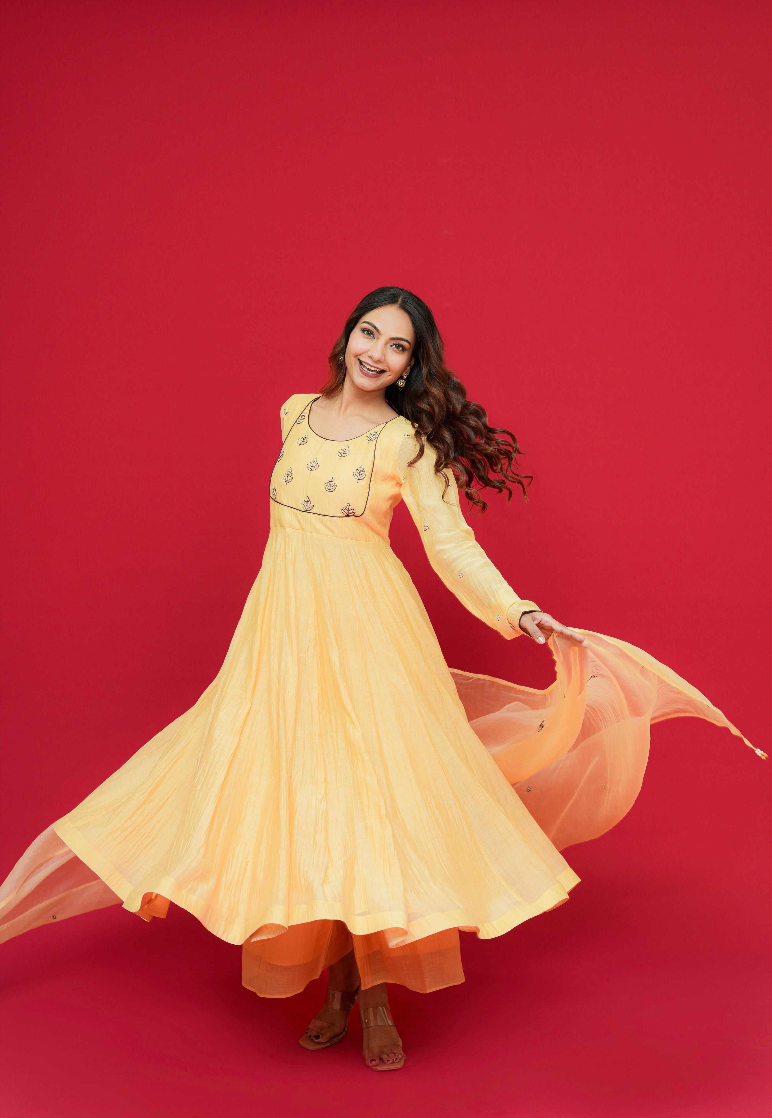 Woman in a Sunny Yellow Mul Chanderi Anarkali Set  on a red background