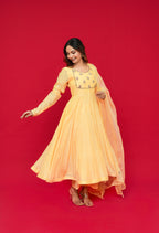 Woman in a Sunny Yellow Mul Chanderi Anarkali Set on a red background