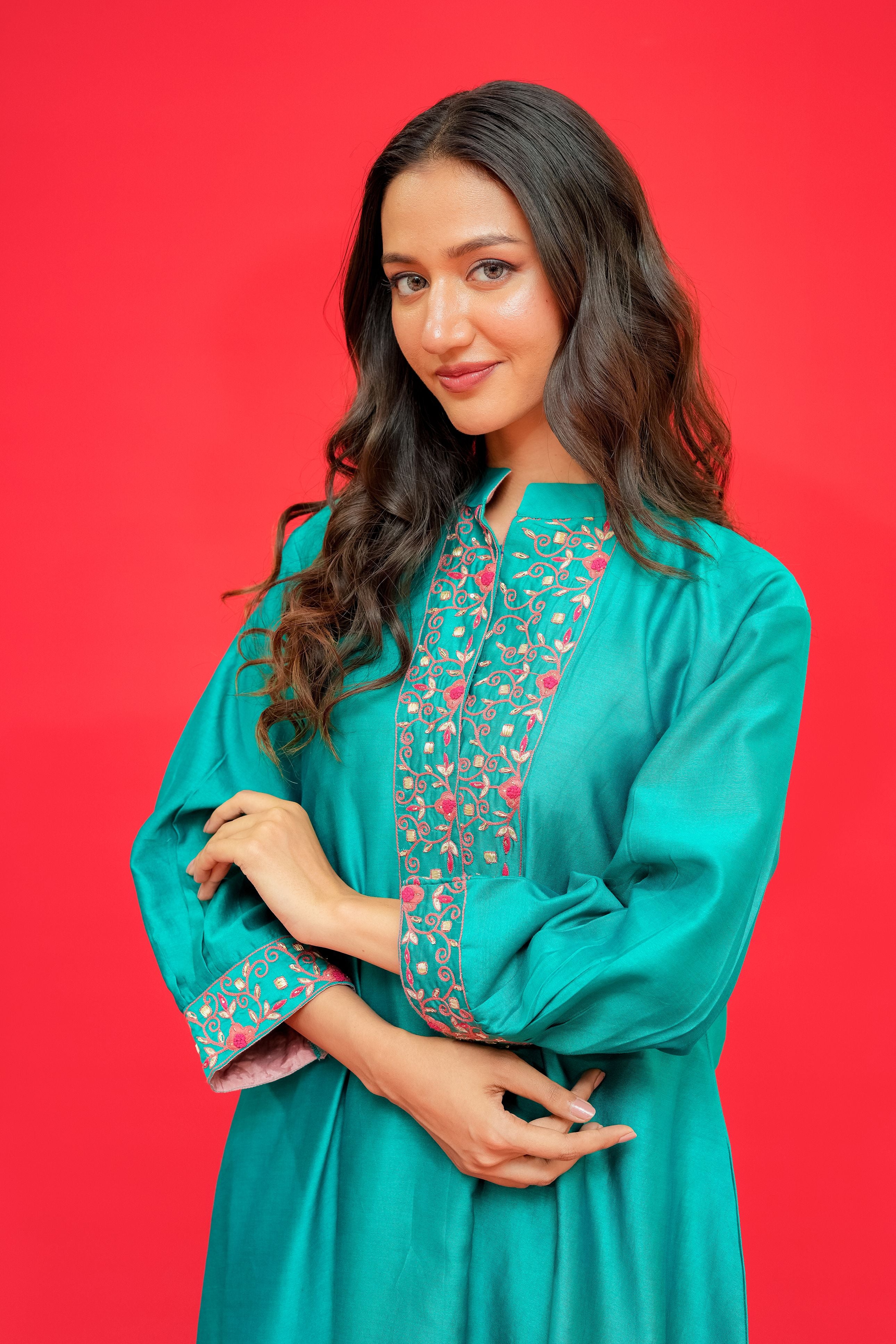 Woman wearing a teal dress with floral patterns on a red background