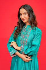Woman wearing a teal dress with floral patterns on a red background