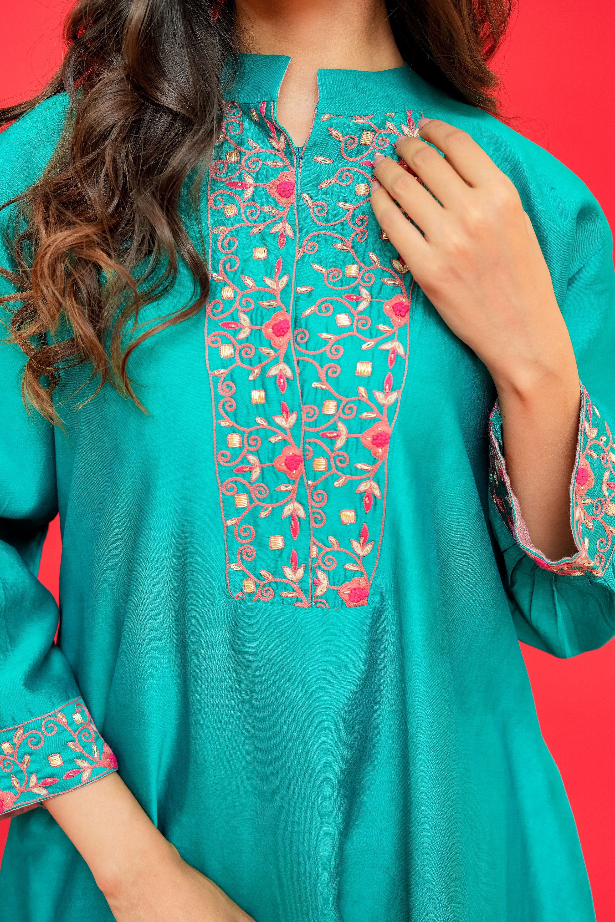 Teal embroidered dress with floral patterns on a red background