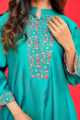 Teal embroidered dress with floral patterns on a red background