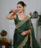 Woman wearing a green saree with gold embroidery in an indoor setting
