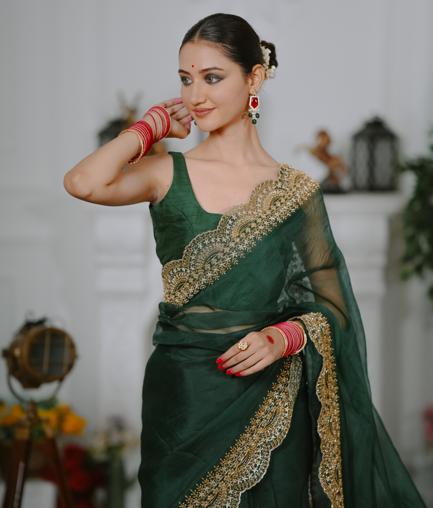 Woman wearing a green saree with gold embroidery in an indoor setting