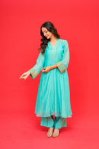 Woman wearing a turquoise traditional outfit on a red background