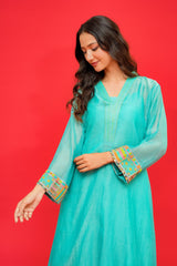 Woman wearing a turquoise traditional outfit with colorful embroidery on a red background