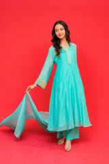 Woman in a turquoise traditional outfit against a red background
