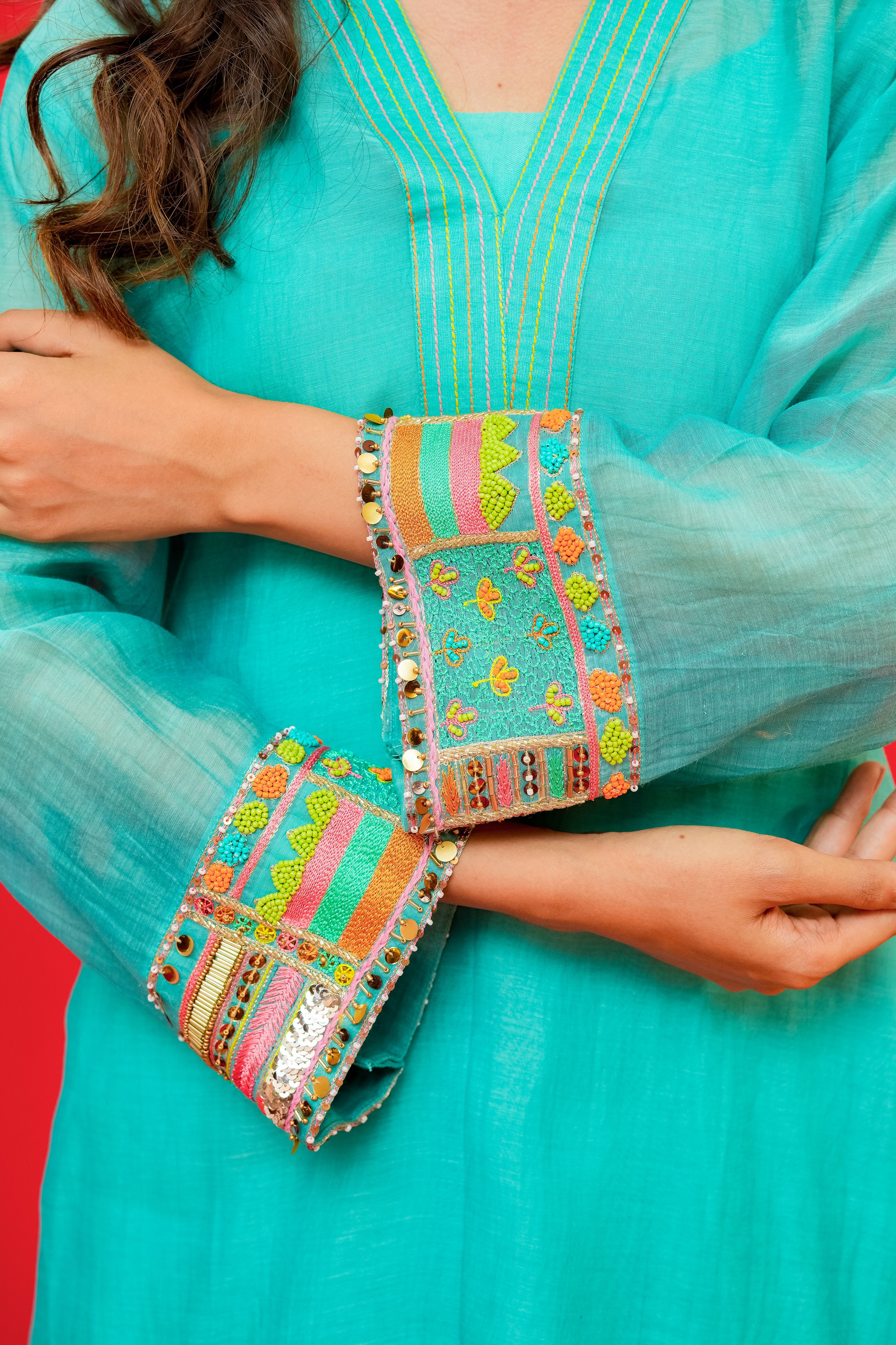 Turquoise traditional outfit with colorful embroidery on a red background