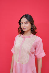 Woman wearing a pink traditional outfit with gold details against a red background