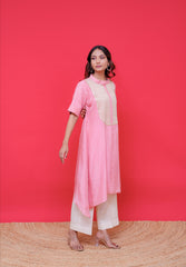 Woman wearing a pink kurta with white pants against a red background