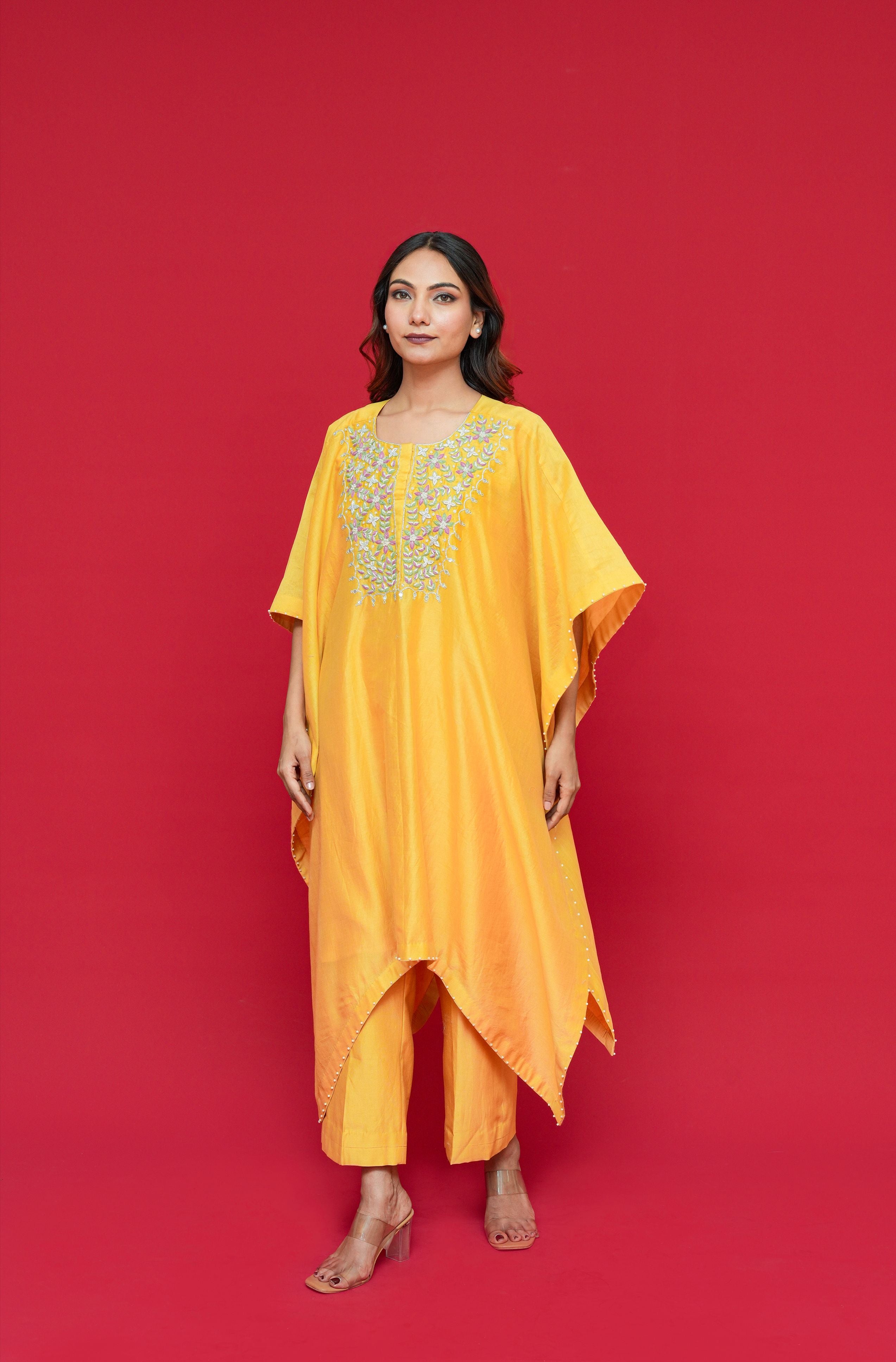 Woman wearing a Yellow Chanderi Silk Kaftan Set  with floral embroidery on a red background